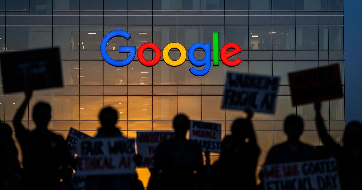 The Google logo with a protest sign in front of it, symbolizing that Google AI workers fired over working conditions.