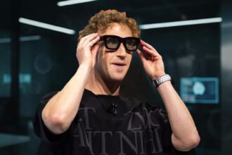 A person wearing stylish Ray-Ban Meta smart glasses, with a futuristic user interface reflected in the lenses because Mark Zuckerberg Believes Smart Glasses Will Replace Your Phone